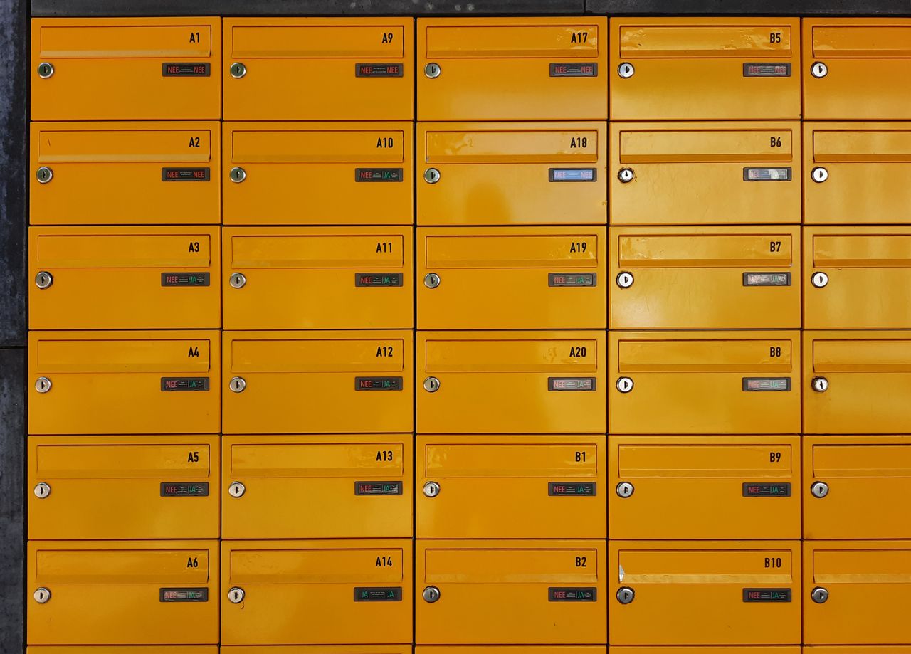 services-01 A grid of vibrant yellow apartment mailboxes with locked doors and numbered labels, offering a modern urban feel.