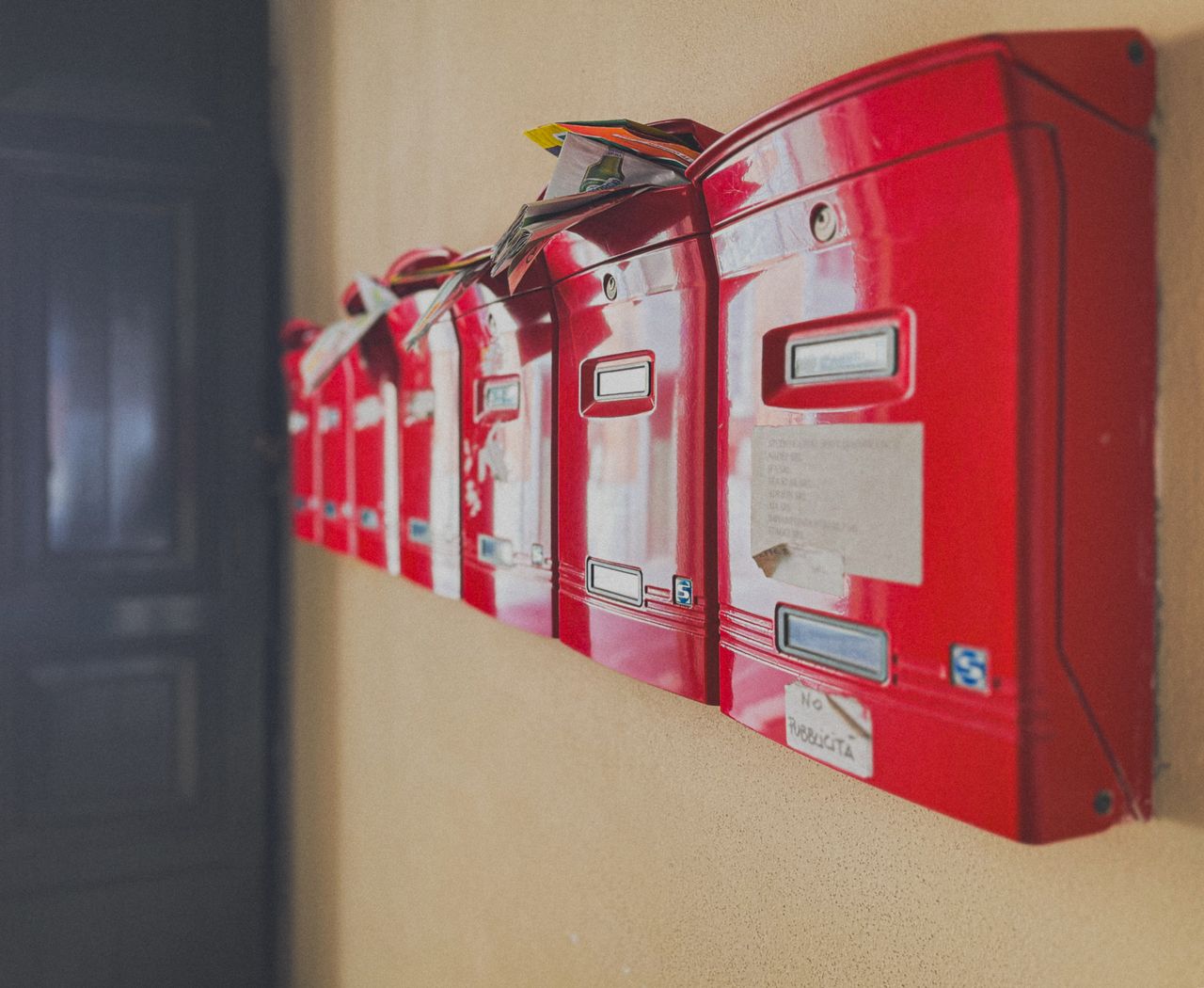 Row of red mailboxes with overflowing mail, depicting communication and correspondence indoors.