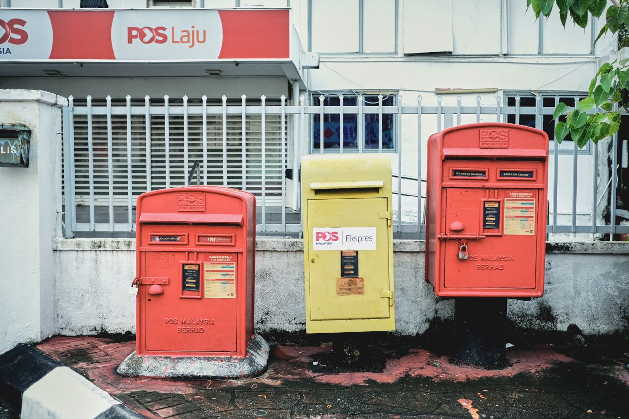 Three vintage mailboxes in Malaysia, showcasing vibrant colors and urban landscape.